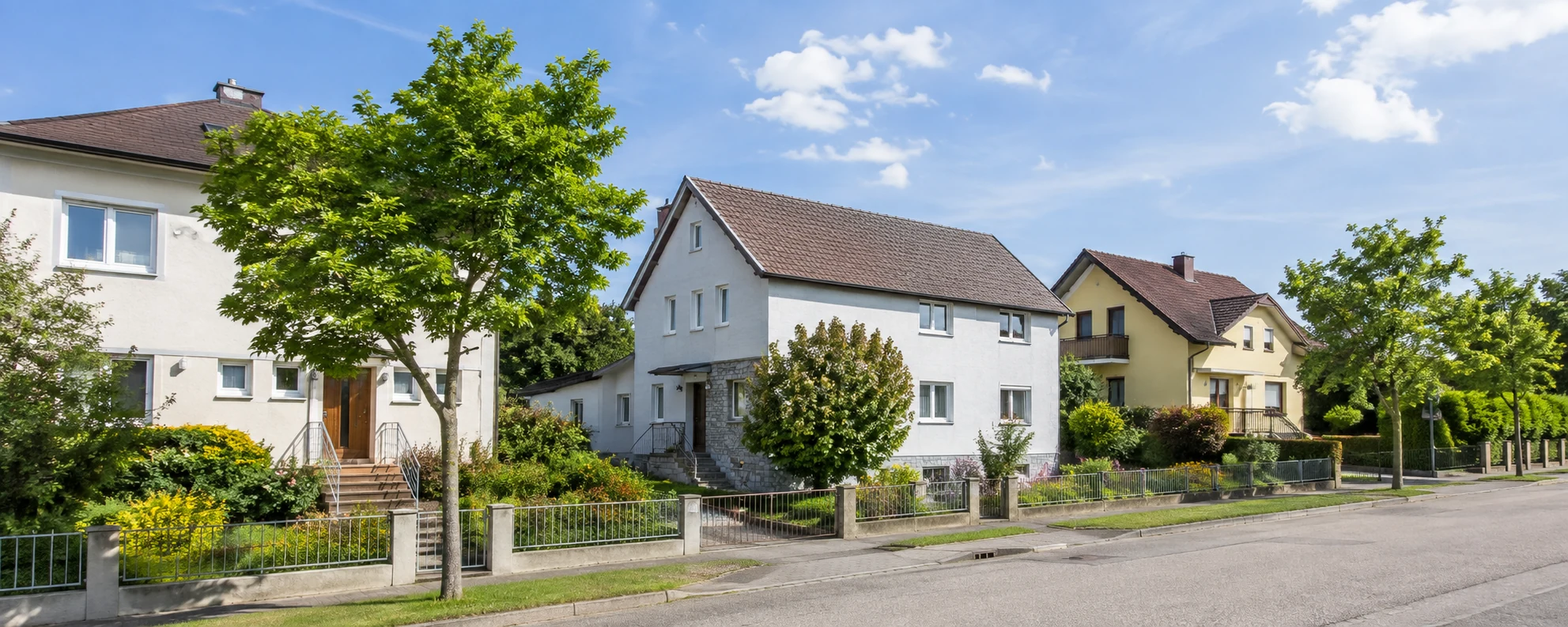 Helle Wohnstraße mit gepflegten Häusern und begrünten Vorgärten